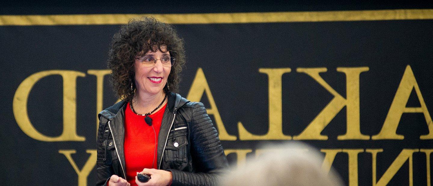 President Ora Hirsch Pescovitz standing in front of a black and gold Oakland University banner.